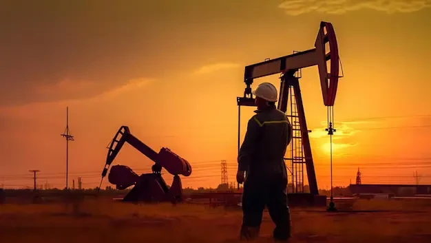 A worker overseeing the efficient operation of oil pumps at sunset